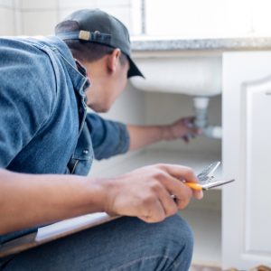 home inspector checking under the kitchen sink